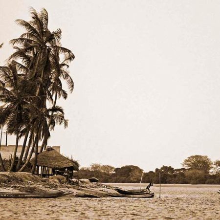 Barques sur une plage bordée de palmiers, en ton sépia.