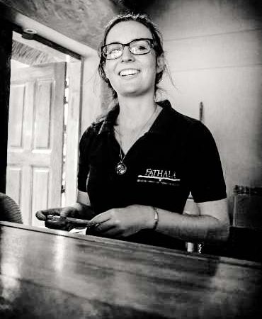 Employée souriante de Fathala en uniforme, derrière le comptoir.