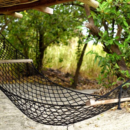 Hamac en filey suspendu sous un abri en bois, entouré de verdure